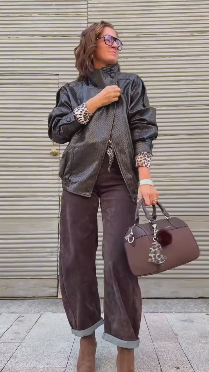 Giacca di pelle nera, camicia leopardata e pantalone marrone